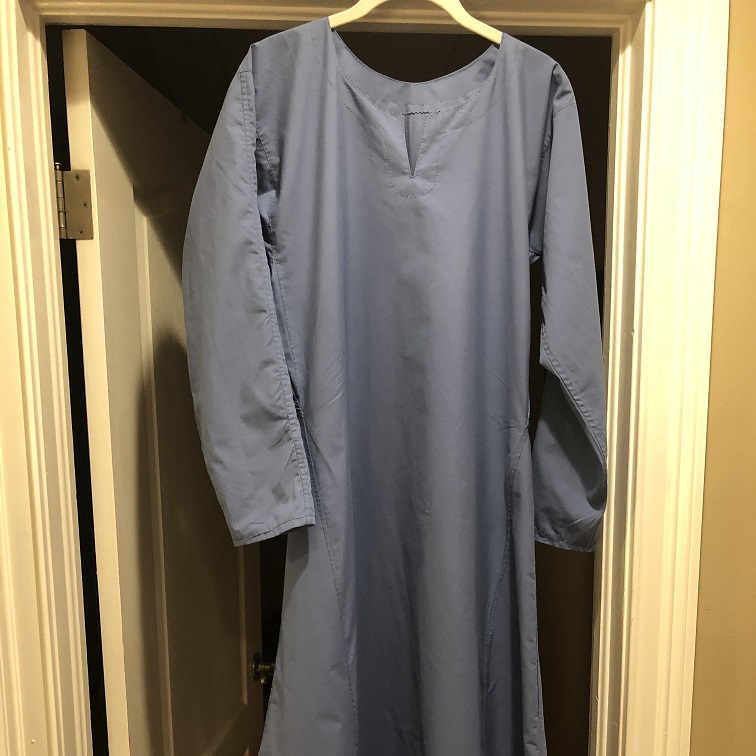 A blue viking underdress made from a bedsheet hanging in a doorway