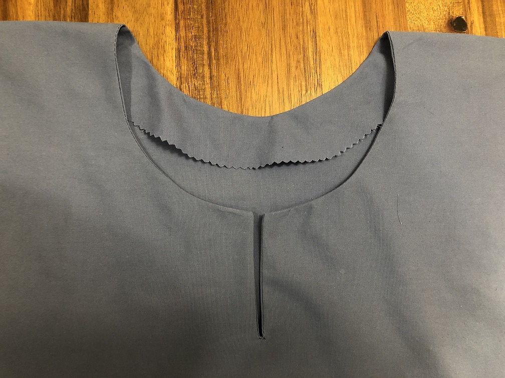 A keyhole neckline on a blue garment with the neck facing visible inside the garment