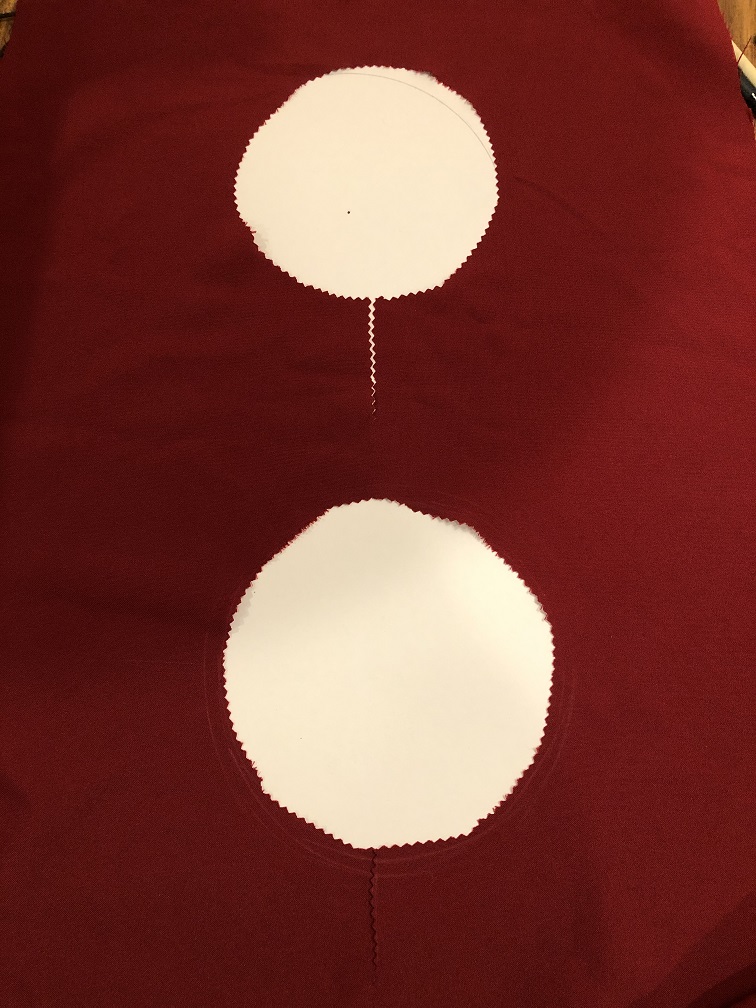 A red piece of fabric with two neckholes of different sizes cut out