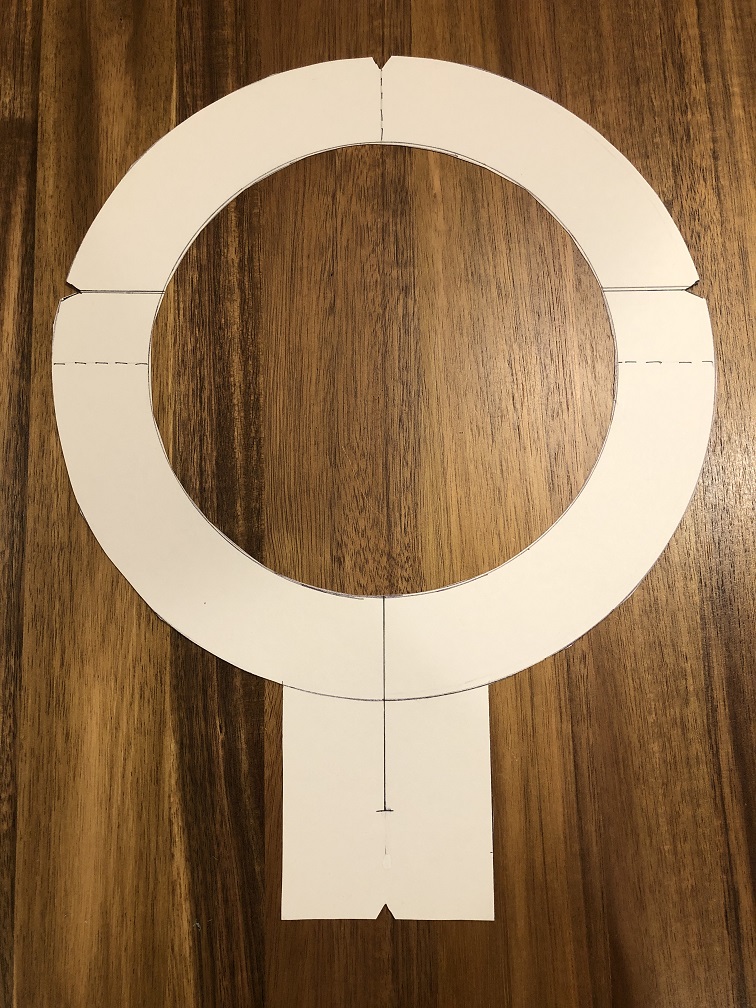 A piece of white posterboard cut out in the shape of a keyhole neck facing pattern 