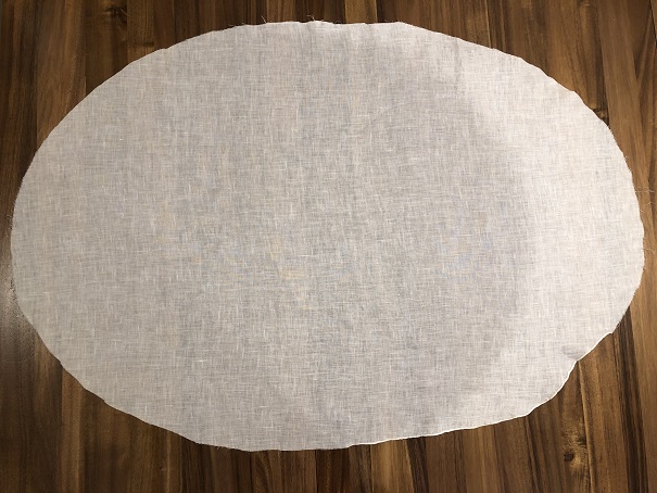 A white linen veil on wood table in the shape of a large oval