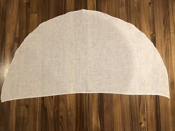 A white linen veil on a wood table in the shape of a large half circle