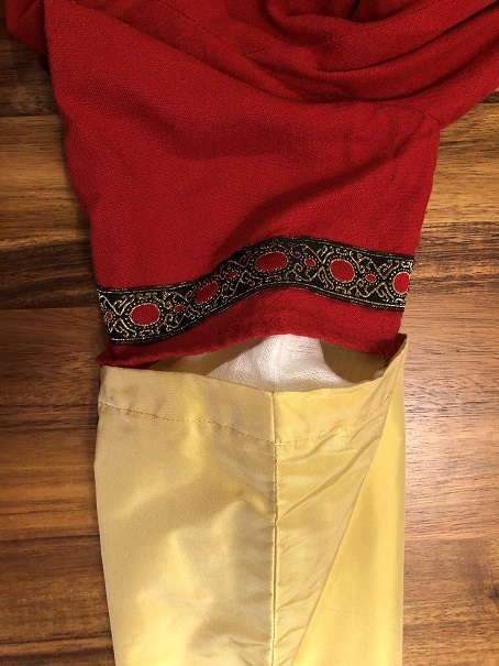 A photo of a gold silk sleeve attached to the short sleeve of a red dress, showing the back seam of the sleeve