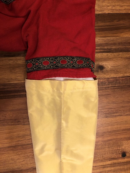 A photo of a gold silk sleeve attached to the short sleeve of a red dress, showing the front fold of the sleeve