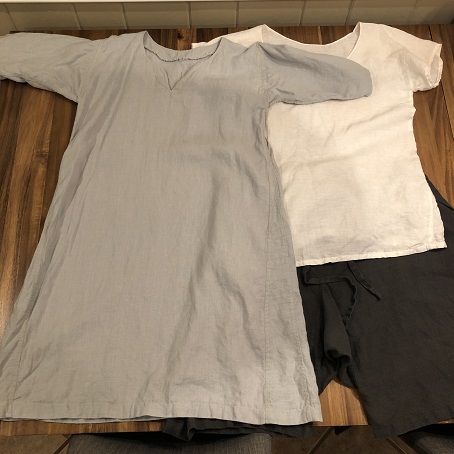 A grey tunic, white shirt, and dark green short braies on a wood table