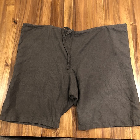 A pair of dark grey linen shorts, called braies, on a wooden table