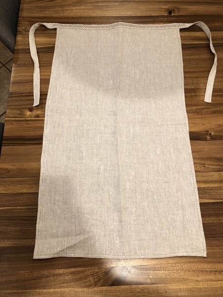 A photo of a linen apron spread out on a wooden table