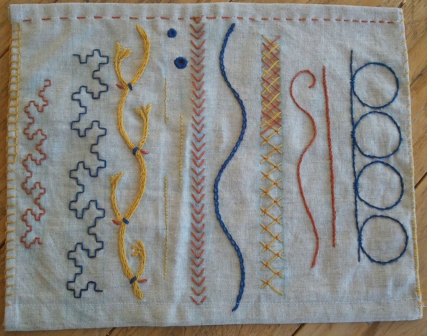 A photo of white cloth with many different types and variations of embroidery stitches