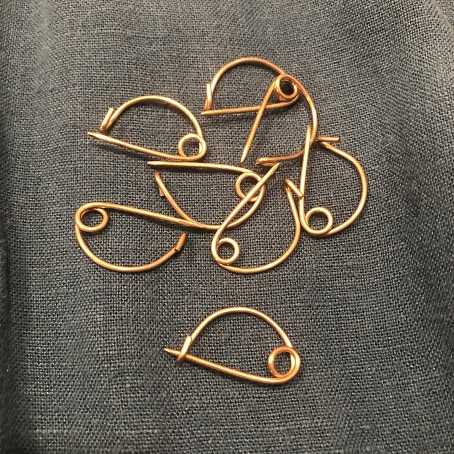 eight small brass fibulae that look almost like safety pins