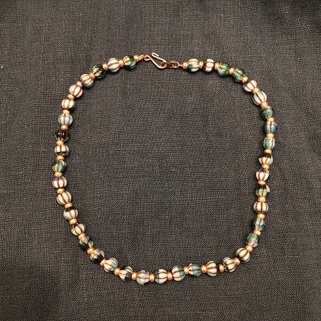 A choker necklace with blue & green melon beads separated by small gold beads