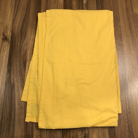 a rectangle of folded bright yellow fabric on a wooden table