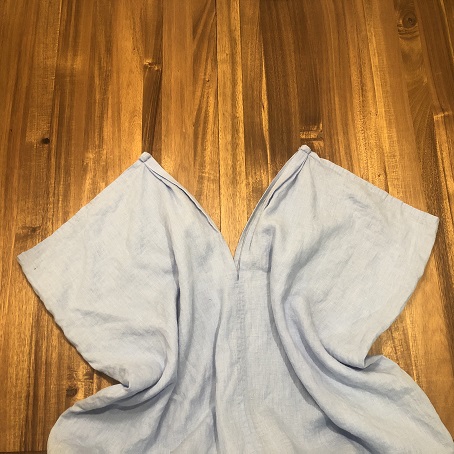 the same blue fabric with the points at the top of the V pulled upwards to show where it fastens at the shoulders and creates armholes with the top of the fabric