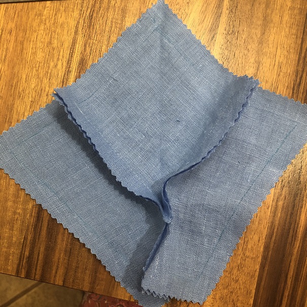 Three pieces of blue fabric - one square and two trapezoids - sewn together to form a larger square